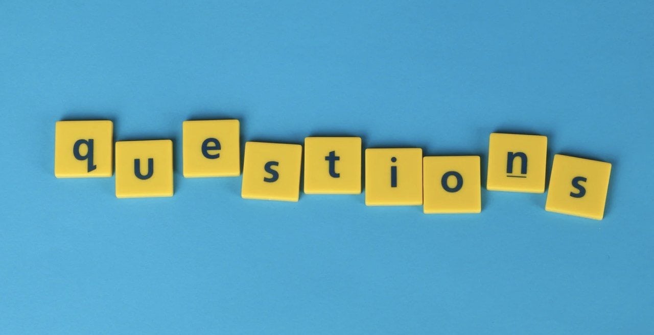 Yellow wordplay pieces put together to create the word "QUESTIONS" with a blue background