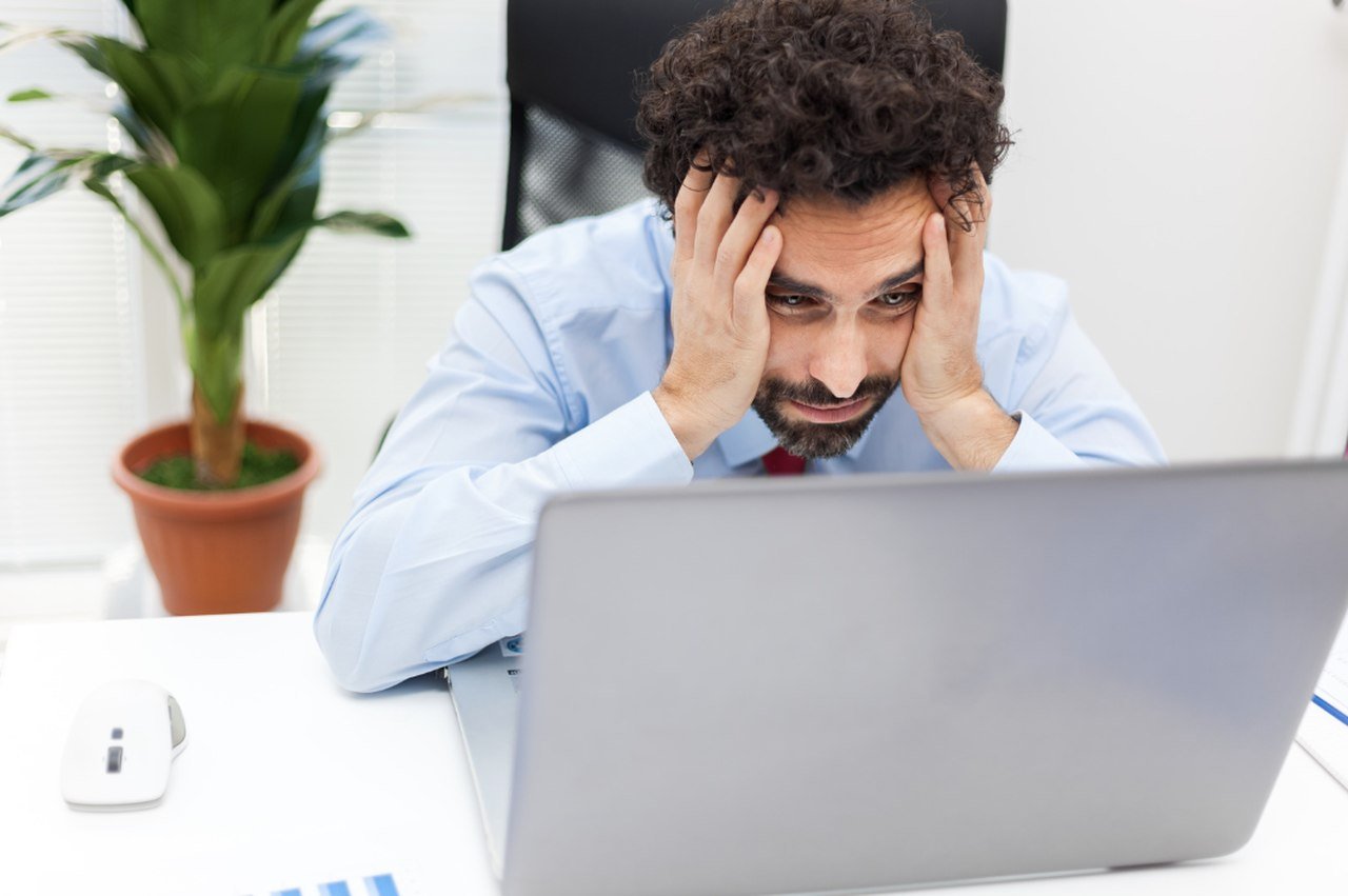 a picture of a frustrated man looking at a laptop screen and searching for the domain errors and website crash reasons