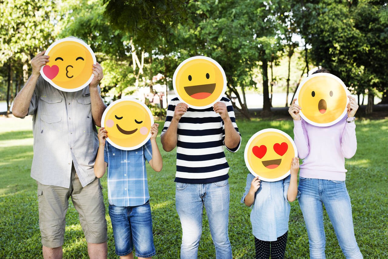 happy family holding up emojis on their faces