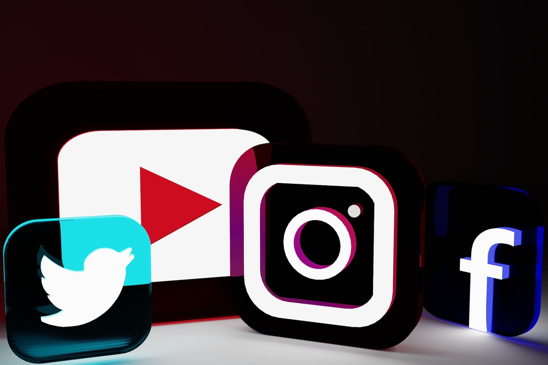 sosyal medya platformları Twitter, YouTube, Instagram & Facebook'un şeffaf ve neon-ışıklı logoları