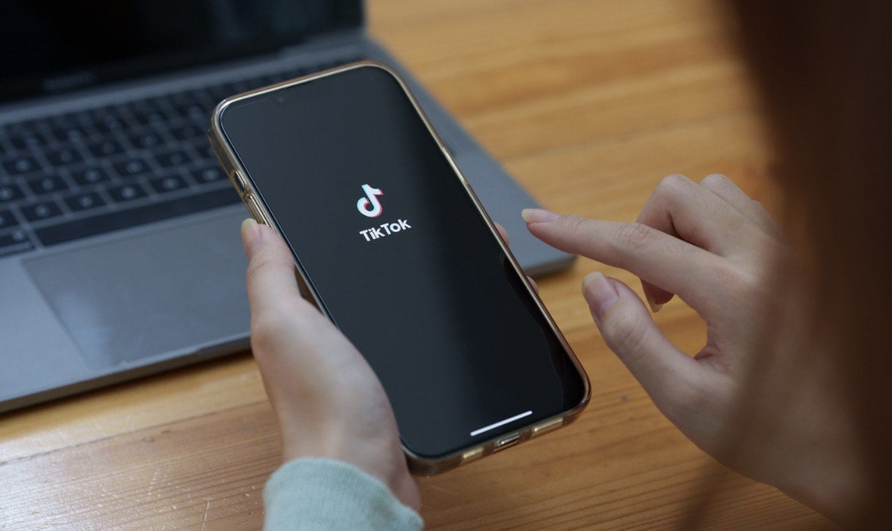 TikTok logosunu gösteren bir cep telefonunu tutan eller