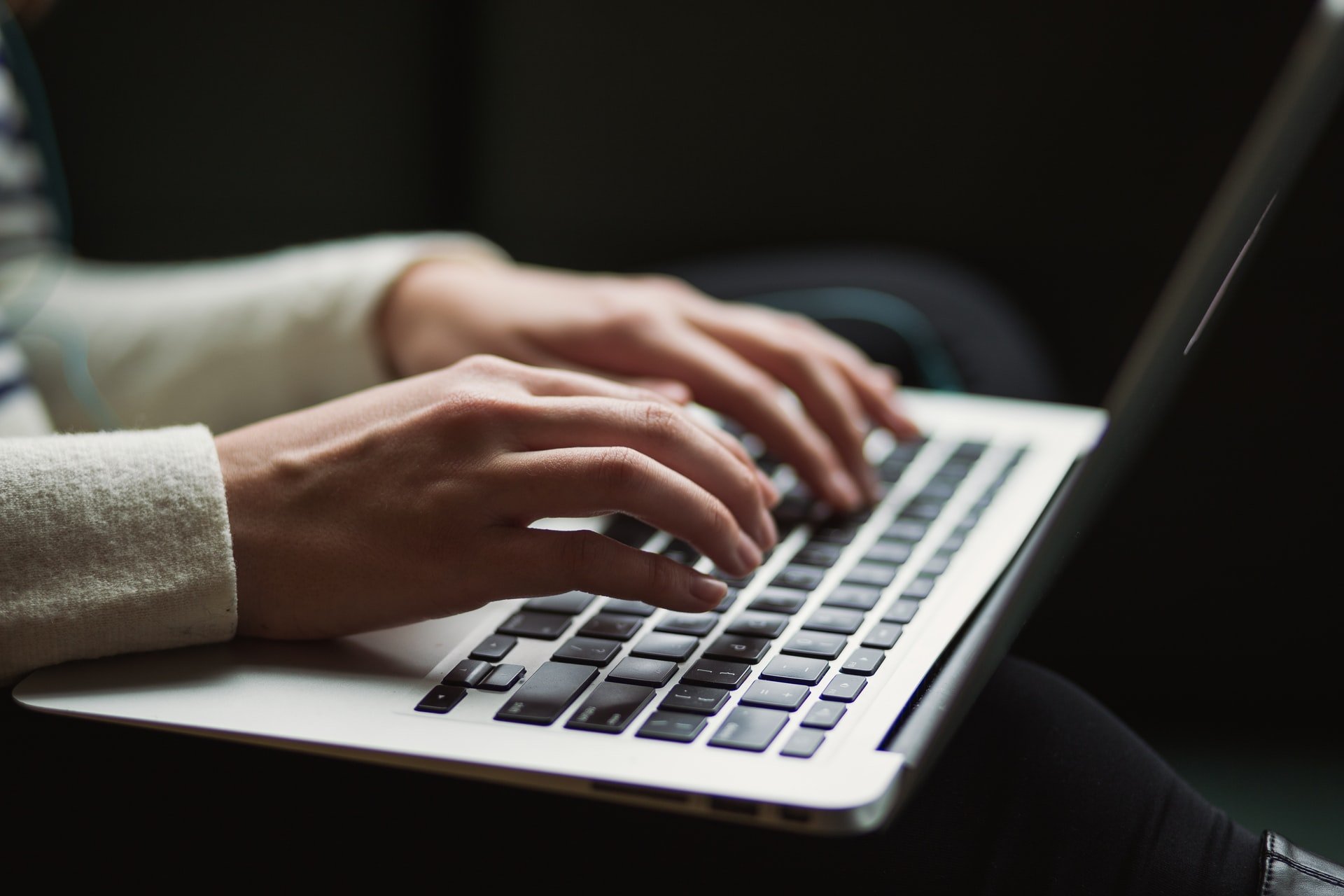 MacBook klavyesinde bir şeyler yazan bir kişi