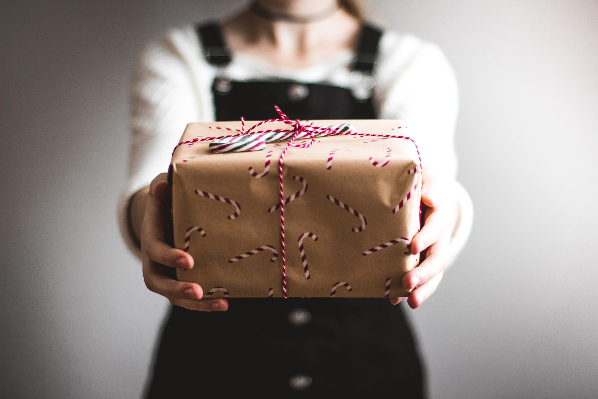 Noel süslemeleriyle kahverengi bir hediye kutusu gösteren tulum giyen bir kız