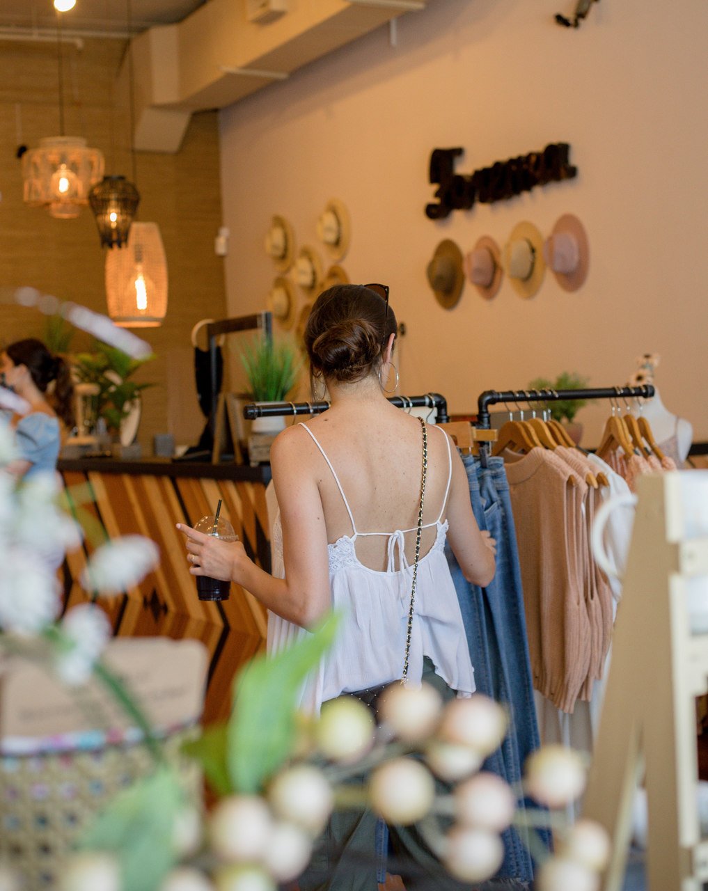 Shopify'da ne satılır giyim mağazada dolaşan ve kıyafetleri kontrol eden bir kadın