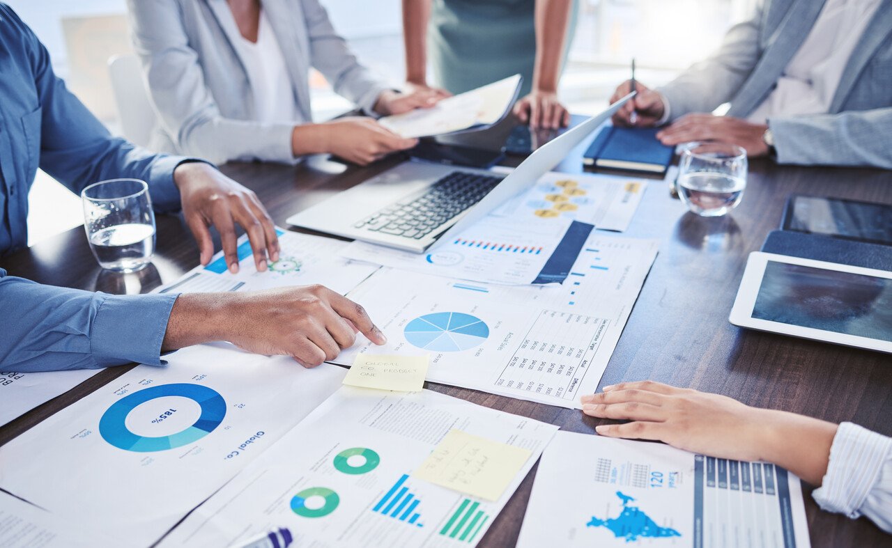 Bir toplantıda masanın üzerindeki analizler ve istatistiklerle çalışan ekip