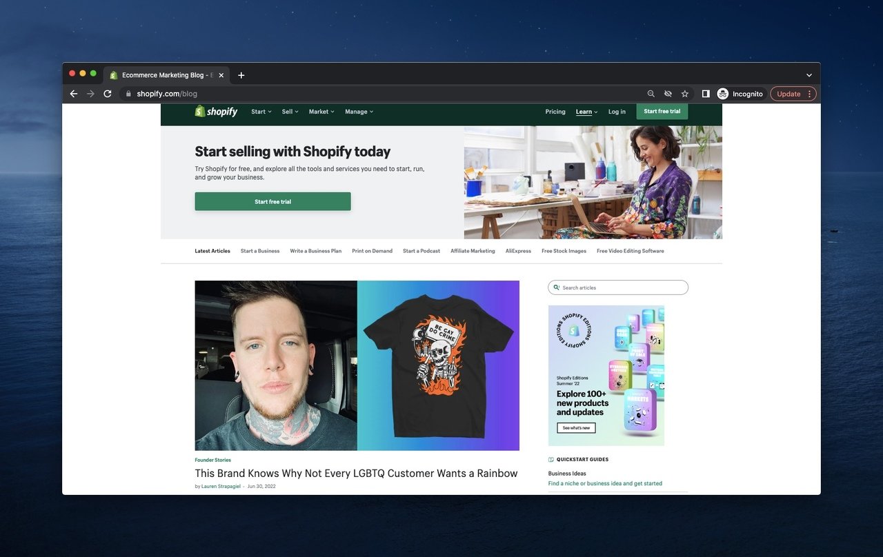 üzerinde 'be gay do crimes' yazılı bir tişört giyen dövmeli bir adamın yanında en son makale kapağı resmi ile ücretsiz deneme çağrısı içeren shopify blog sayfası