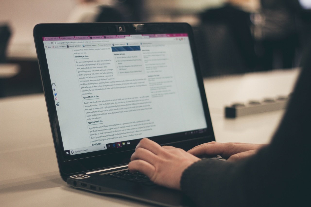 laptop ekranında bir blog yazısı ve onun üzerinde çalışan ellerle e-ticaret blog yazma süreci