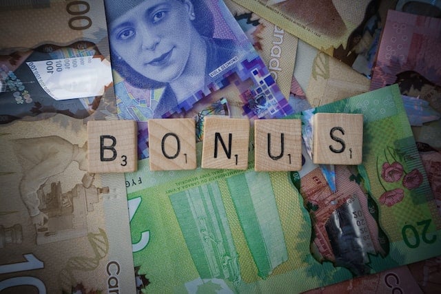Çeşitli kâğıt paraların üzerinde yan yana dizili "bonus" harflerinden oluşan scrabble taşları