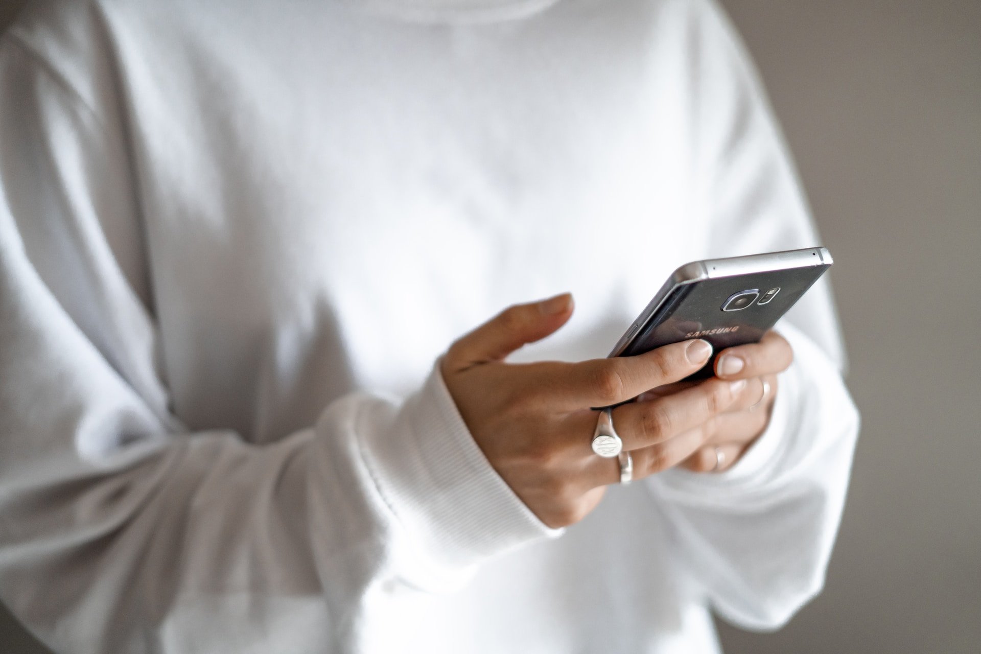 SMS marketing campaign reach as a woman in a white jumper holds her phone