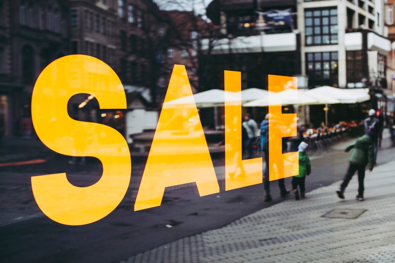 The word ‘Sale’ on the store window reflects the people and the street.