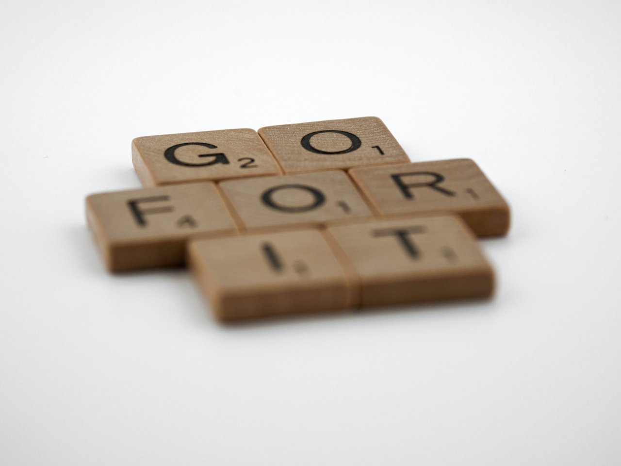 Scrabble tiles forming “Go For It” on a white background