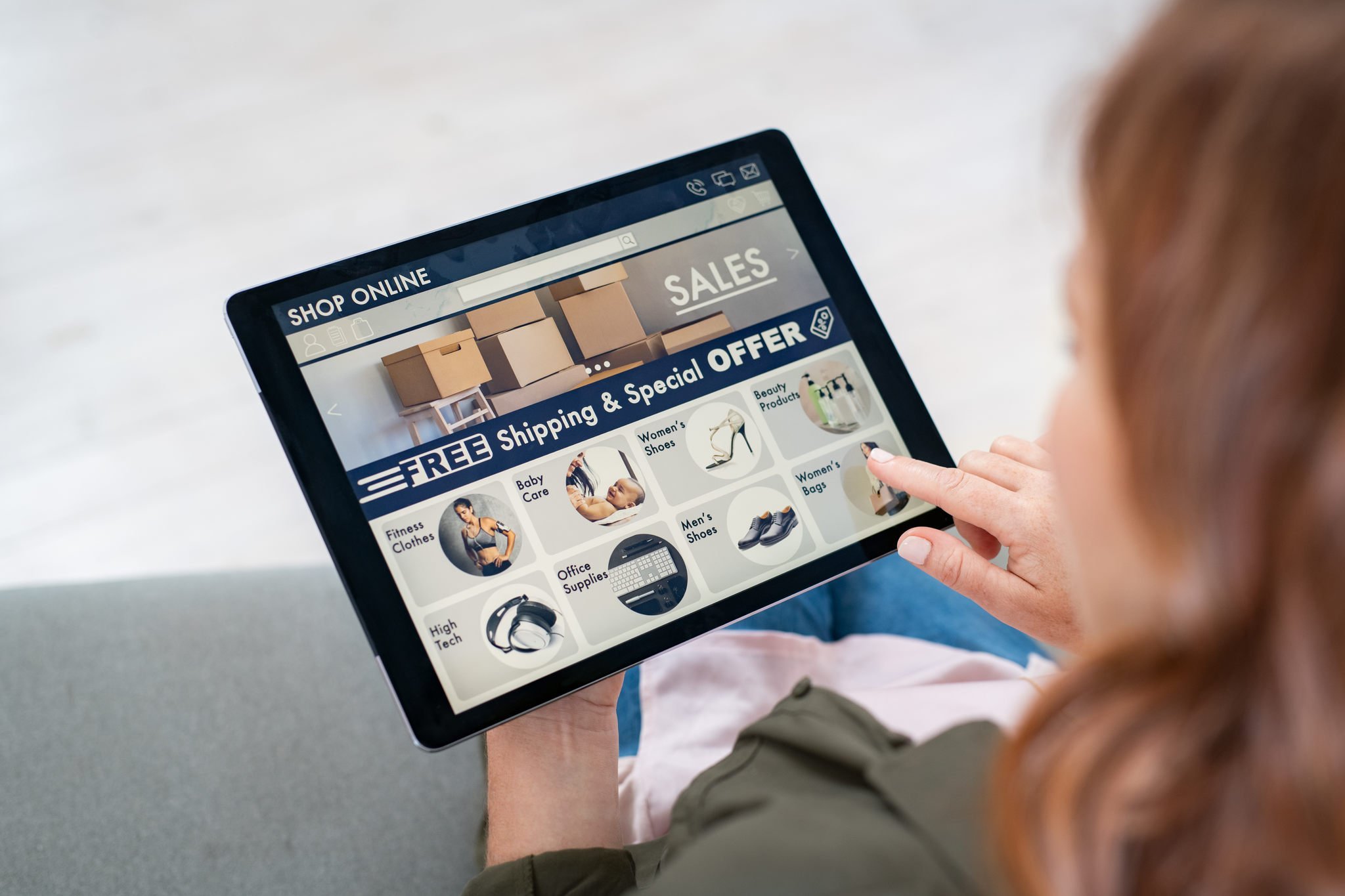 A woman shopping online using a tablet looking at product categories and special offers