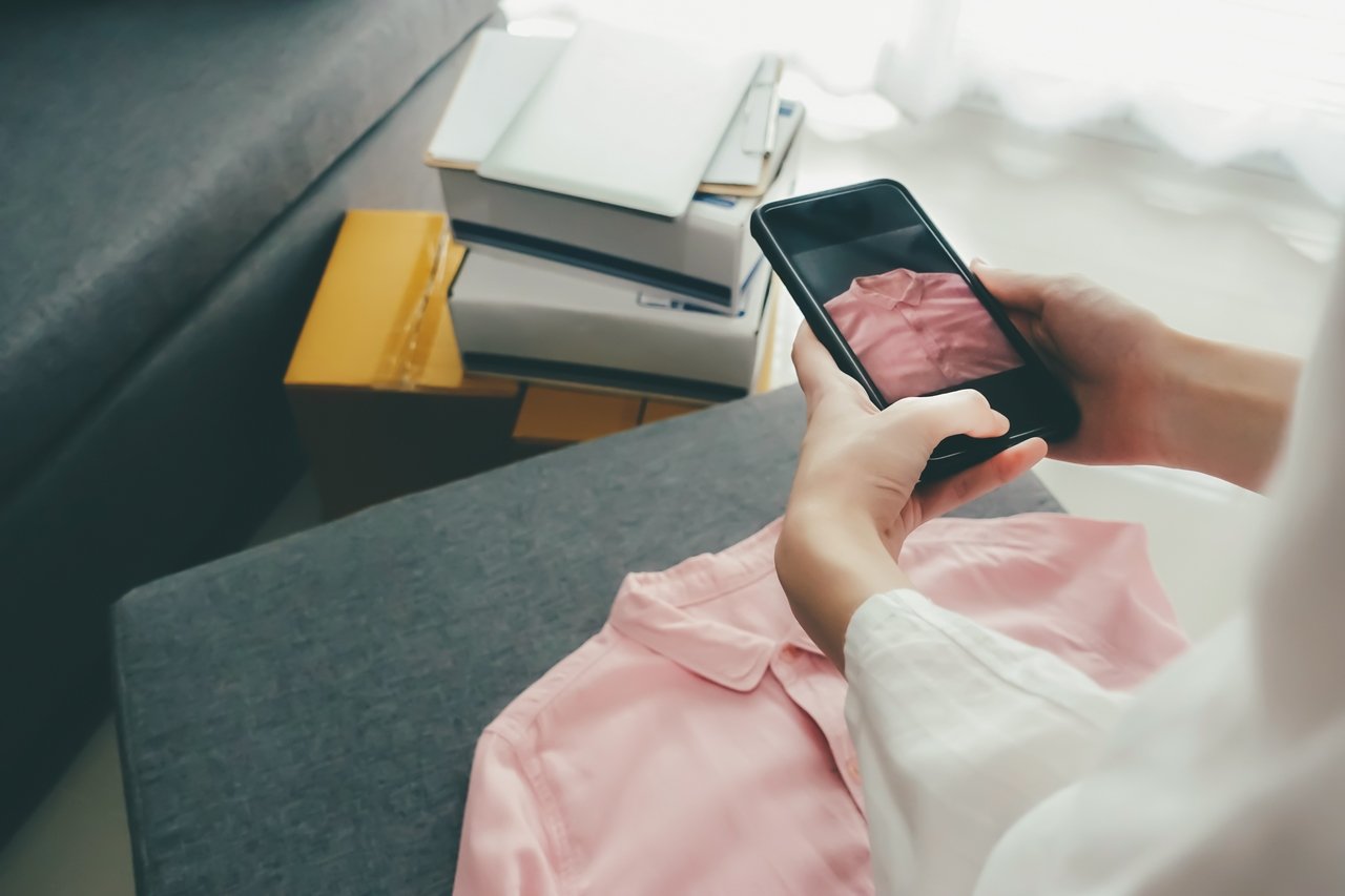 Woman taking a picture of clothes to sell online through referral marketing