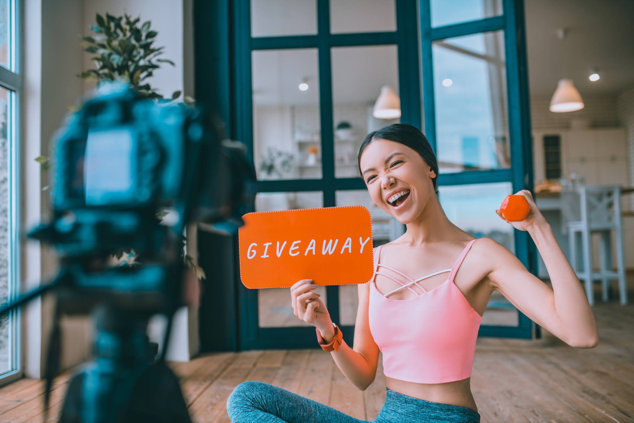 fitness blogger hosting a product giveaway holding an orange sign and a dumbbell