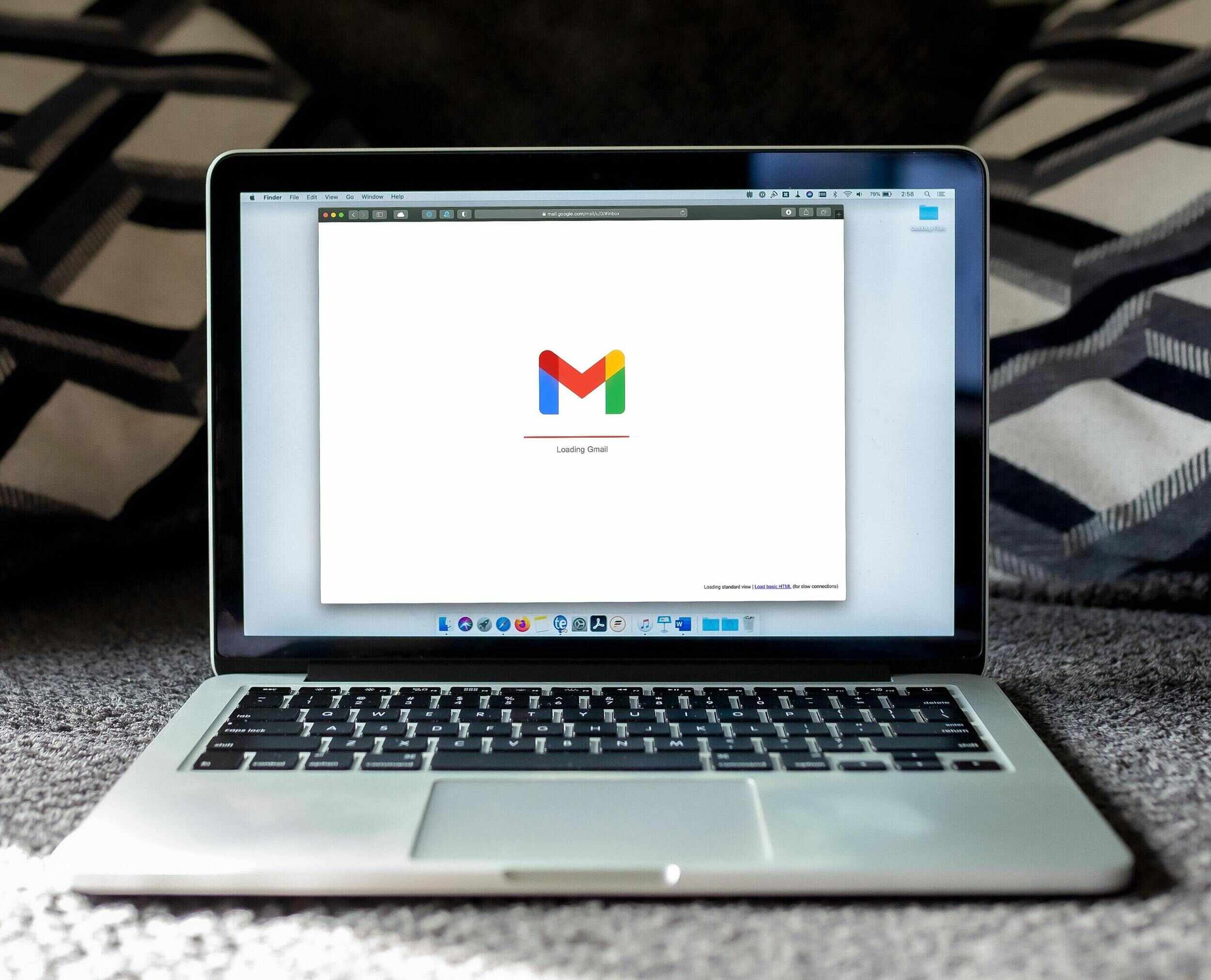 Halı zemin üzerinde Gmail logosu bulunan bir dizüstü bilgisayar