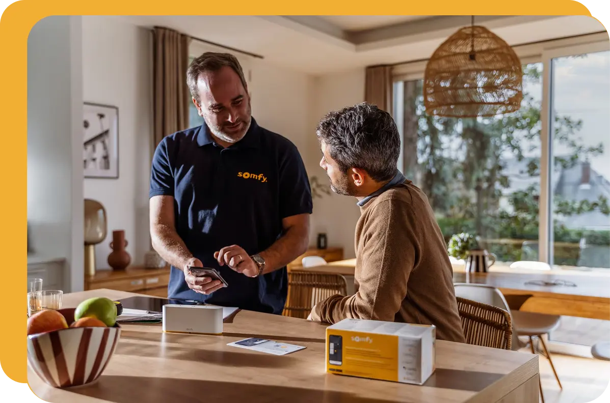 Somfy technician demonstrating smart-home solution to homeowner in a modern living room