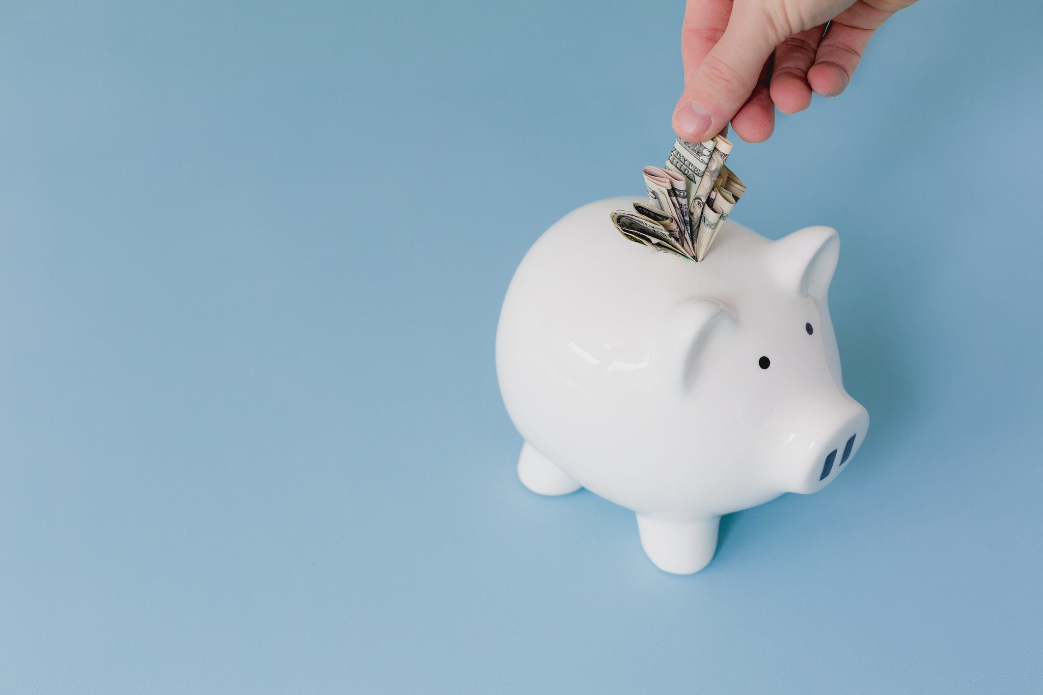 White piggy bank on blue background representing holiday budget planning