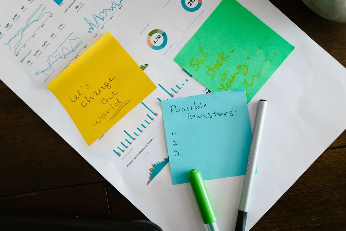 Sticky notes and a business strategy plan laid over marketing performance charts