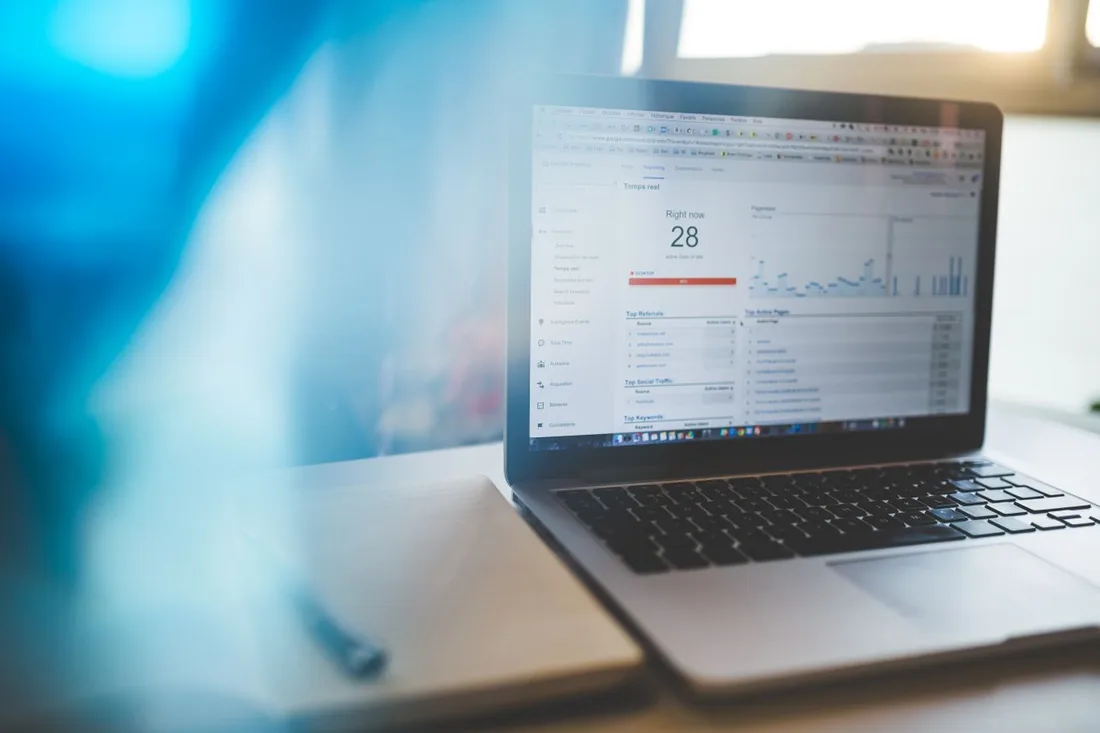 Laptop screen showing a Google Analytics dashboard with real-time traffic and top keywords