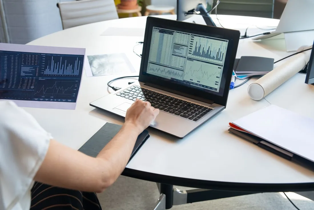 Person at a desk analyzing website performance data and charts on a laptop