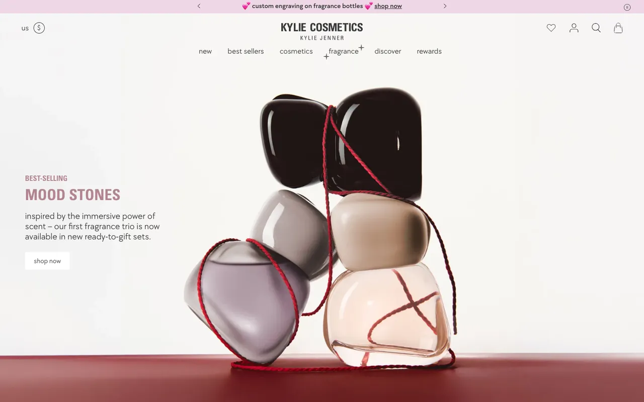 Kylie Cosmetics homepage first screen: a sculptural stack of fragrance bottles tied with red string, labelled Best-selling Mood Stones, with a shop now button