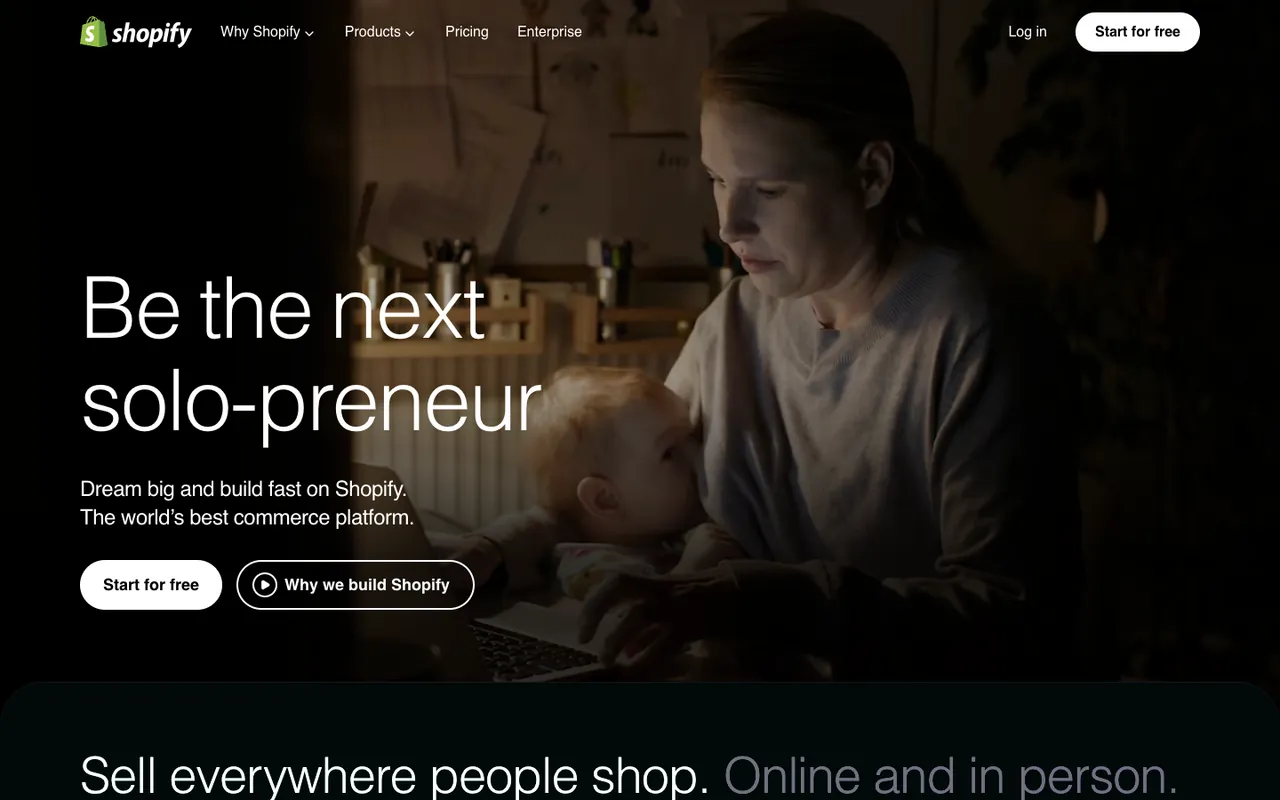 Shopify homepage first screen: video of a parent working at a laptop with a baby, headline Be the next solo-preneur, with Start for free and Why we build Shopify buttons